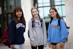 3 students standing in front of a building on the Homewood Campus in Baltimore, Maryland.