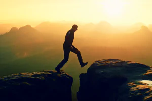 Person walking across a gap between two boulders