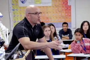 Teacher speaking to students in a classroom.